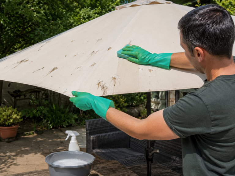 Nettoyage de fientes de pigeon sur un parasol de jardin avec des gants et une éponge