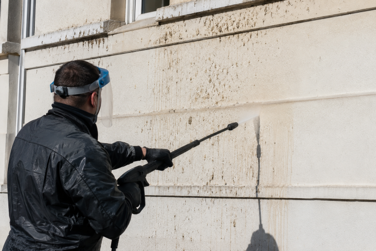 Nettoyage de fientes de pigeon sur une façade peinte avec équipement de protection