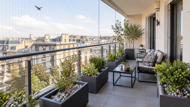 Balcon moderne aménagé avec filet discret, jardinières protégées et mobilier rangé pour limiter la présence des pigeons